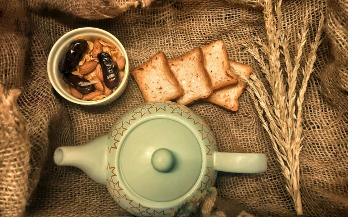 white ceramic teapot beside brown and white food on white ceramic round plate
